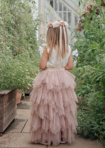 young girl in gardens wearing pretty dress in latte colours