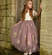 Young girl in a floral dress standing against a stone wall