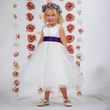 Girl wearing a white Dolly dress with purple sash