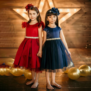 two young girls holding hands wearing party dresses