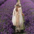 girlin a pale pink dress walking through a lavender field