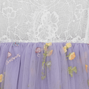 Lace top and purple tulle skirt with floral embroidery on a white lace background