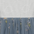 Blue embroidered skirt with floral patterns on a textured white background