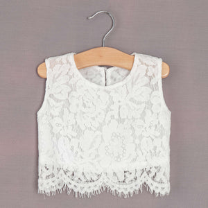 White lace top on a wooden hanger against a gray background