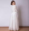 Young girl wearing a white lace dress against a plain background