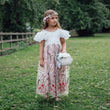 Young girl in a floral dress standing in a grassy field