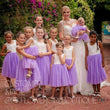 Bride with a baby and flower girls in matching dresses outdoors.