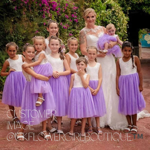 Bride with a baby and flower girls in matching dresses outdoors.
