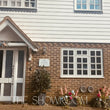 Front exterior of a house with white siding and brick lower facade, featuring a white door, window, and a large overlaid text watermark reading 'THE SHOWROOM'.