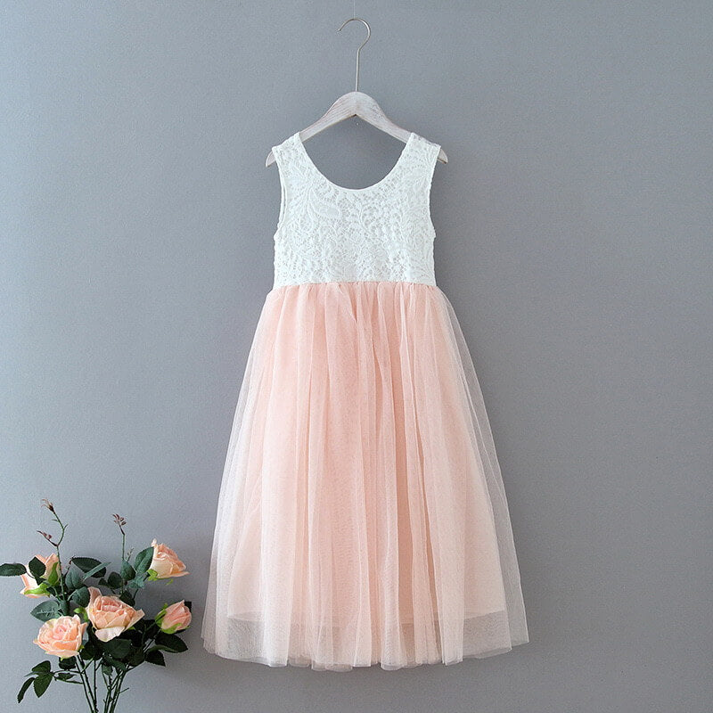 White lace top and blush tulle skirt dress on a hanger against a grey background with flowers.
