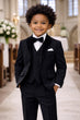 Child in a formal black suit standing in a church setting