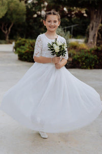 Young girl in a white dress holding flowers outdoors