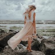 girl standing on rock on beach in a Baby Bohemian Serendipity Dress - Blush