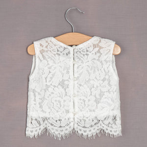 White lace vest on a wooden hanger against a gray background