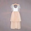 Two-tone dress with white top and beige skirt on a hanger against a gray background