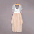 Two-tone dress with white top and beige skirt on a hanger against a gray background