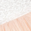Close-up of apricot champagne fabric with a textured pattern on a white lace background