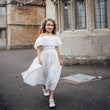 Young girl in a white dress standing in front of a historic building.