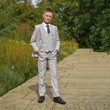 boy in a garden wearing a stone coloured 5 Piece Suit from uk flower girl boutique 