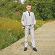 boy in a garden wearing a stone coloured 5 Piece Suit from uk flower girl boutique 