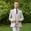 boy in a garden wearing a stone coloured 5 Piece Suit from uk flower girl boutique 