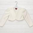 White bolero jacket on a hanger with a visible brand label against a light wooden background