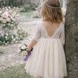 toddler in a lace dress holding a bouquet in a garden setting