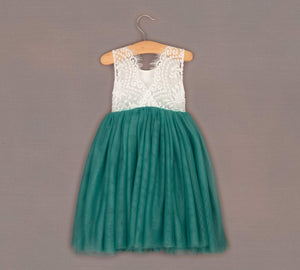 Teal and white dress on a hanger against a gray background
