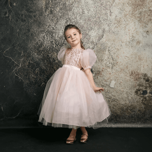 Dark haired girl wearing a blush coloured party dress from UK Flower Girl Boutique
