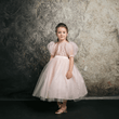 Dark haired girl wearing a blush coloured party dress from UK Flower Girl Boutique