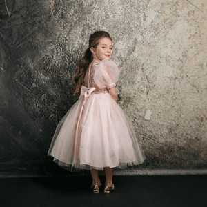 Dark haired girl wearing a blush coloured party dress from UK Flower Girl Boutique