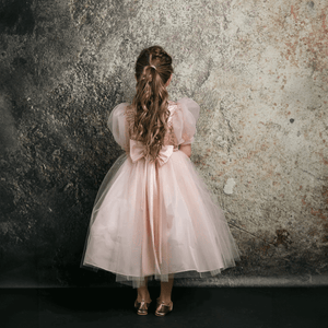 Long haired girl wearing a blush coloured party dress from UK Flower Girl Boutique