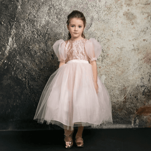 Dark haired girl wearing a blush coloured party dress from UK Flower Girl Boutique