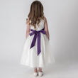 purple bow on back of girls white dress