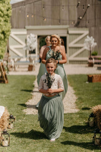 Young flower girl followed by bridesmaids