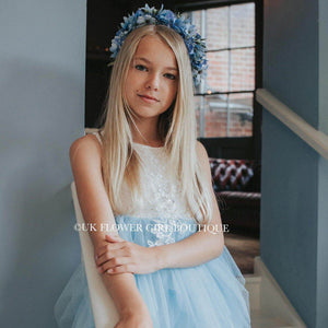 Girl in put flower girl boutique party dress with a blue garland in her hair