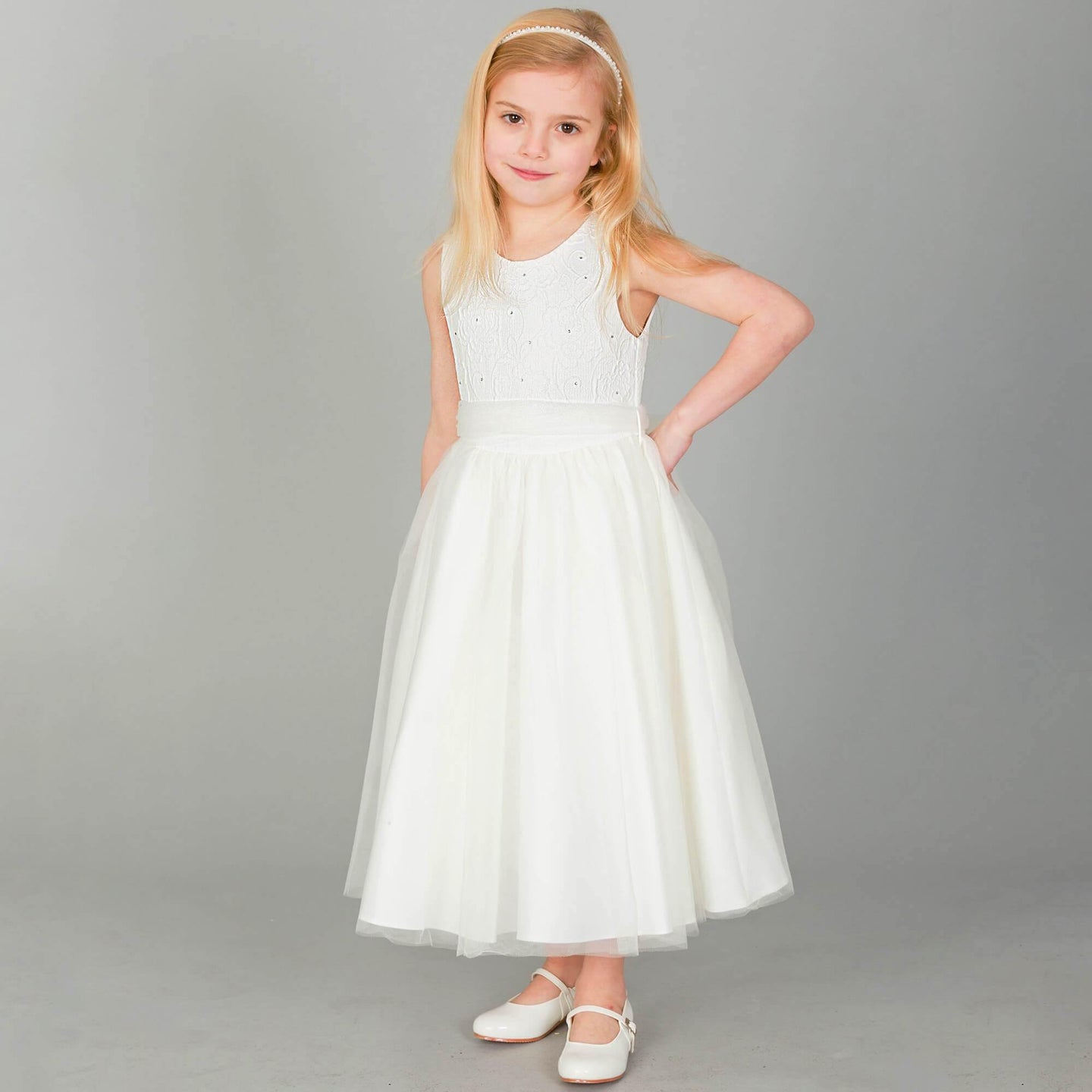Blonde girl wearing ivory coloured party dress  and whit party shoes